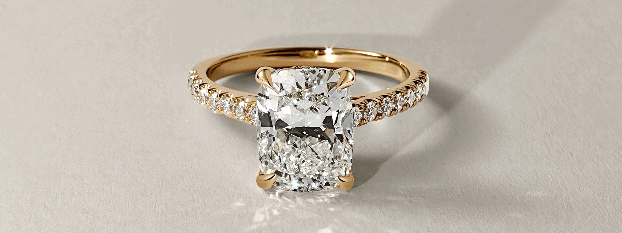 Elongated cushion cut diamond engagement ring with cathedral style band in yellow gold
