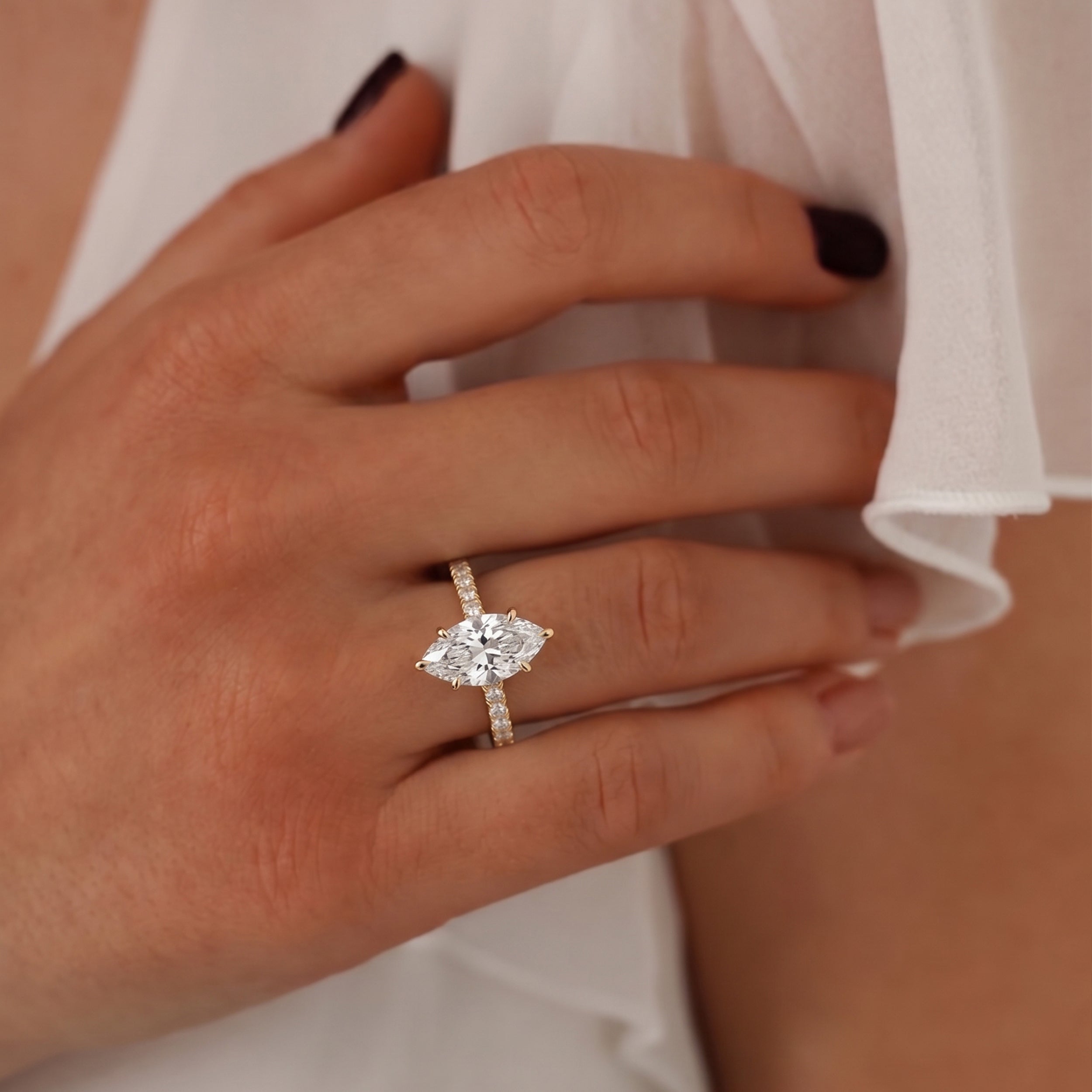 marquise cut diamond cathedral ring with pave band in yellow gold shown on hand