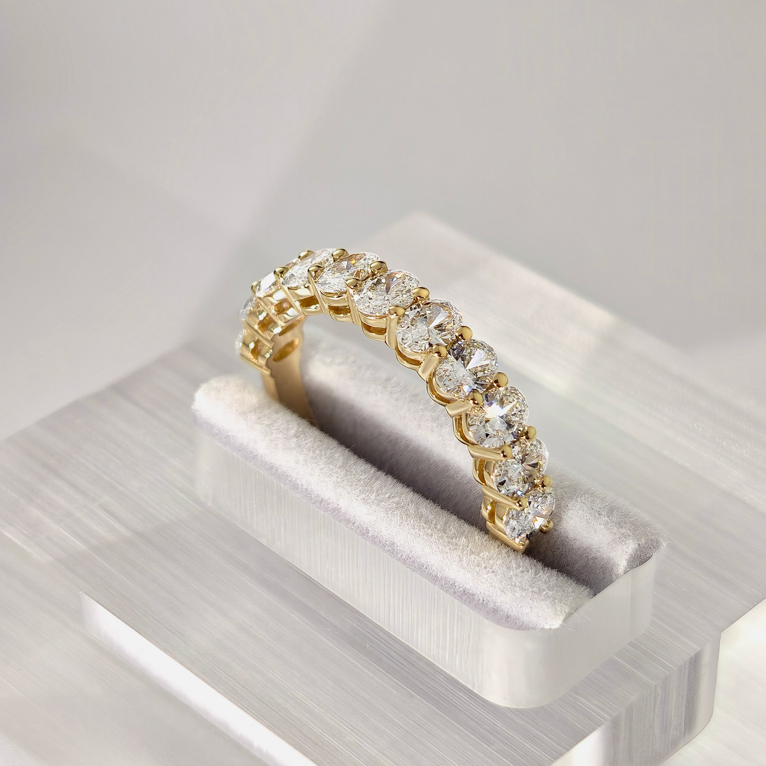 oval diamond eternity ring with basket setting in yellow gold stand on ring box